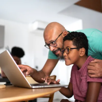Latinx father and teenage son using a laptop together